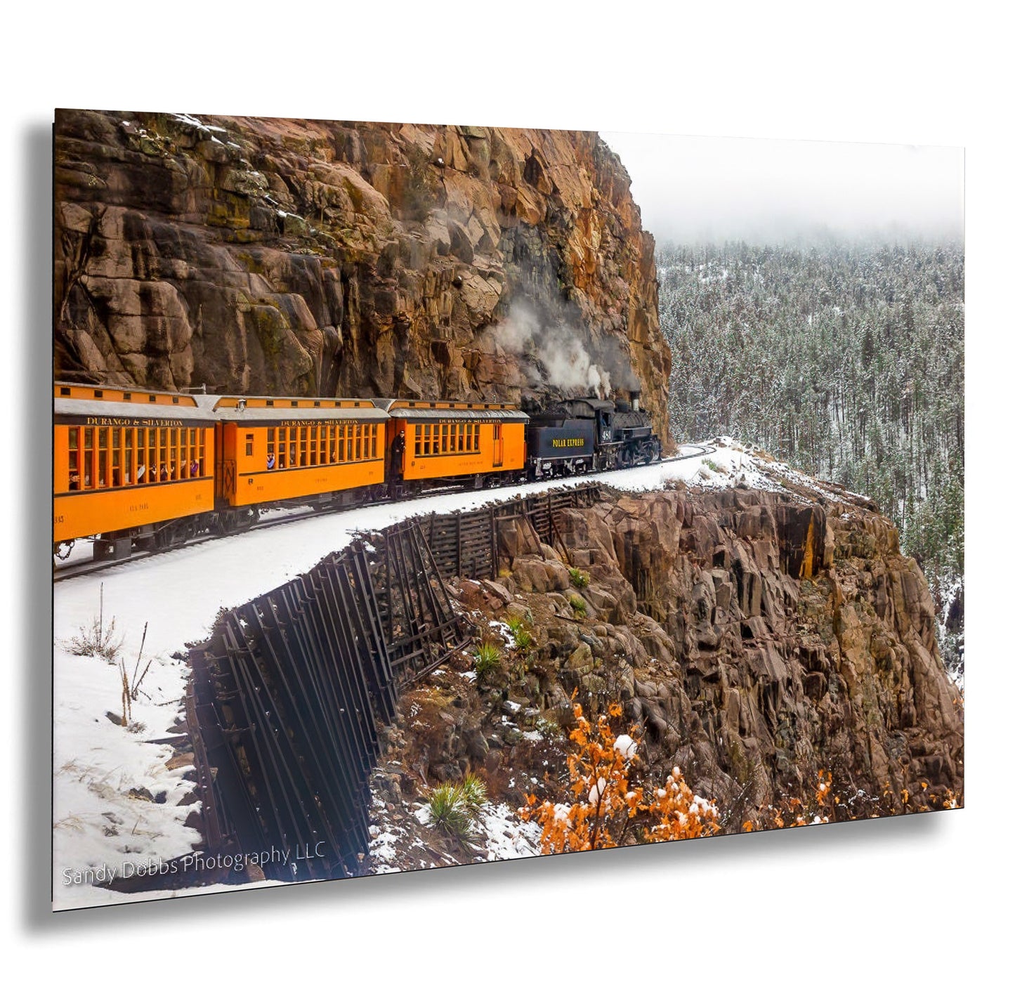 a train traveling down tracks next to a mountain