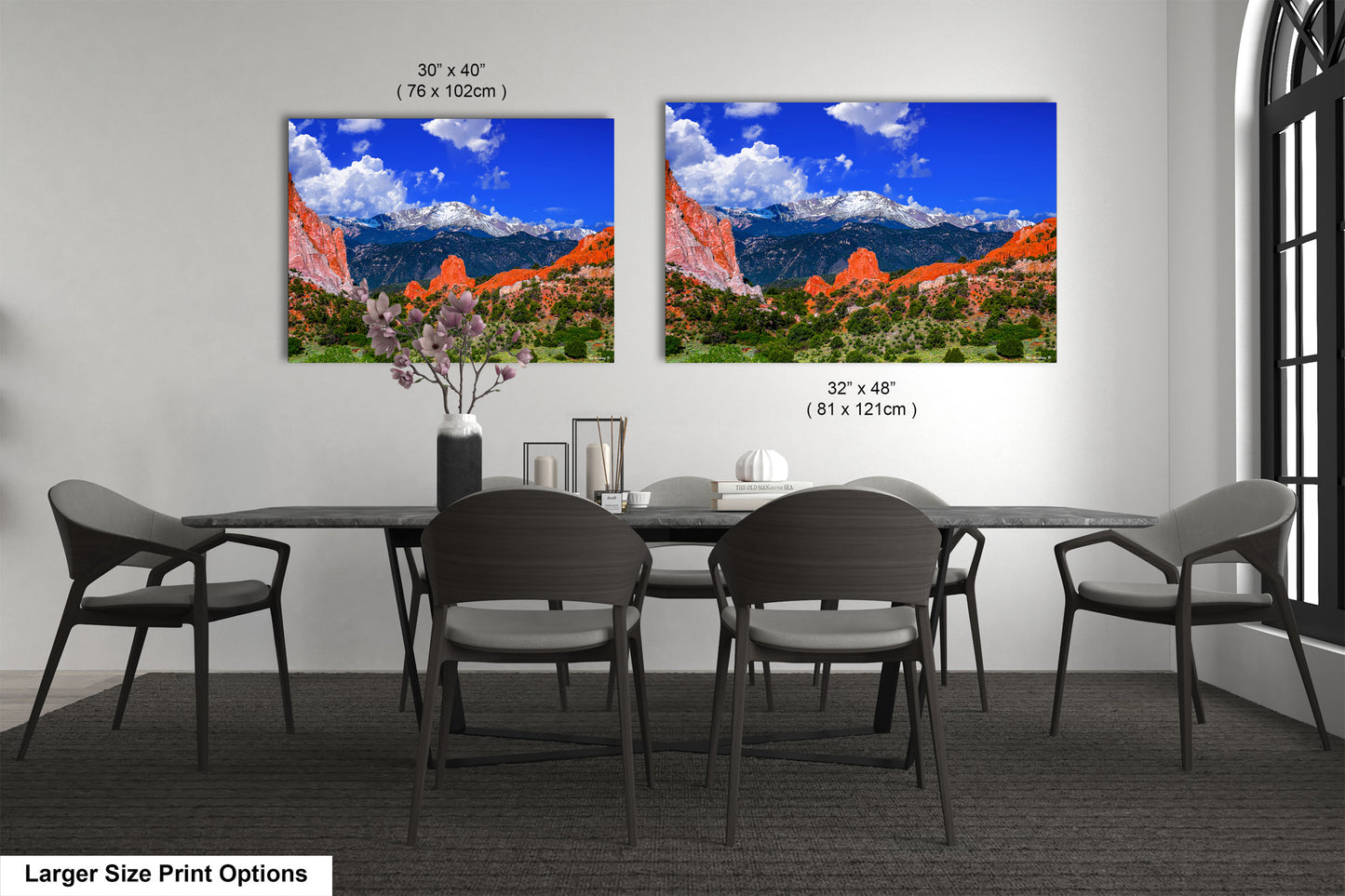 a dining room table with four chairs and two pictures on the wall
