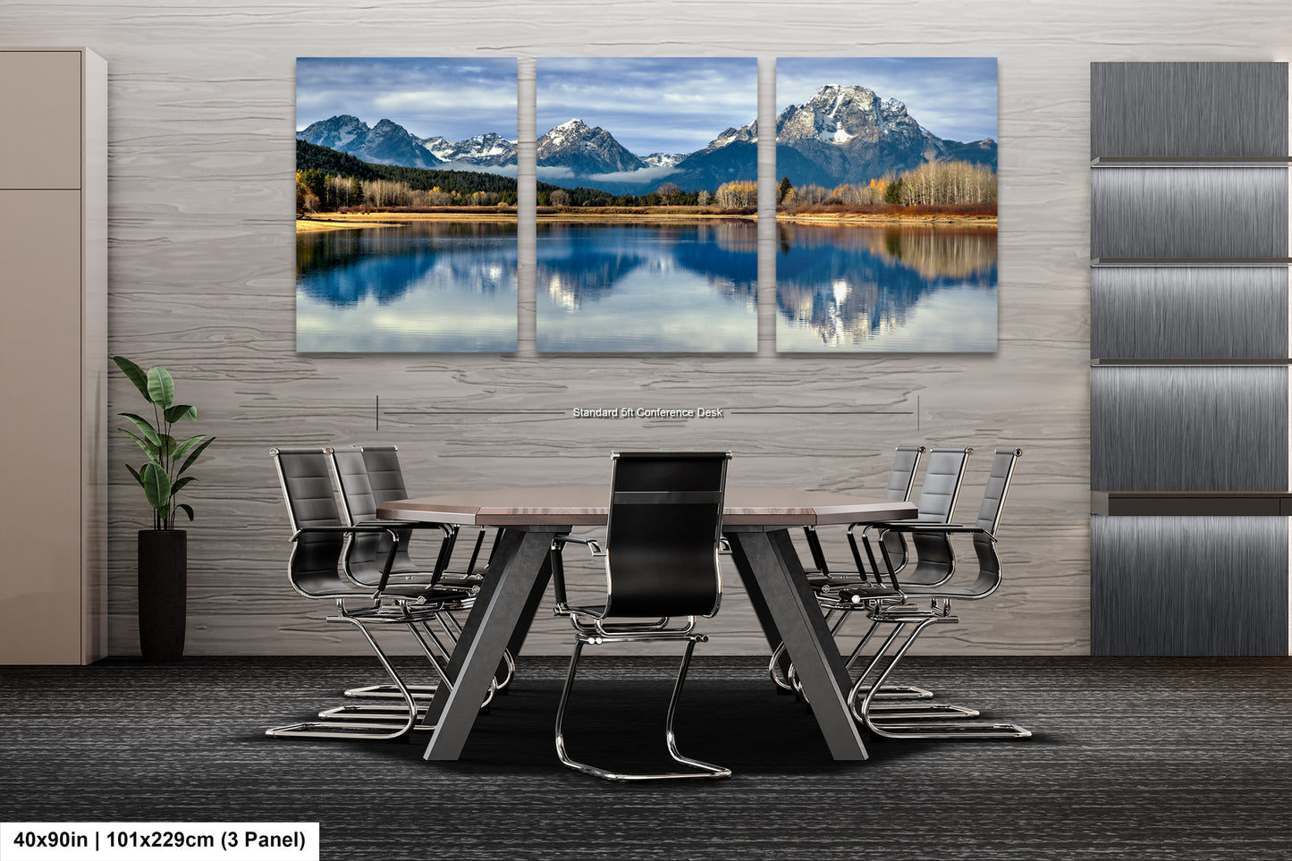 A modern office space with a large, three-panel landscape painting depicting a serene mountain lake and forest scene. The painting is mounted on the wall above a wooden table surrounded by chairs.