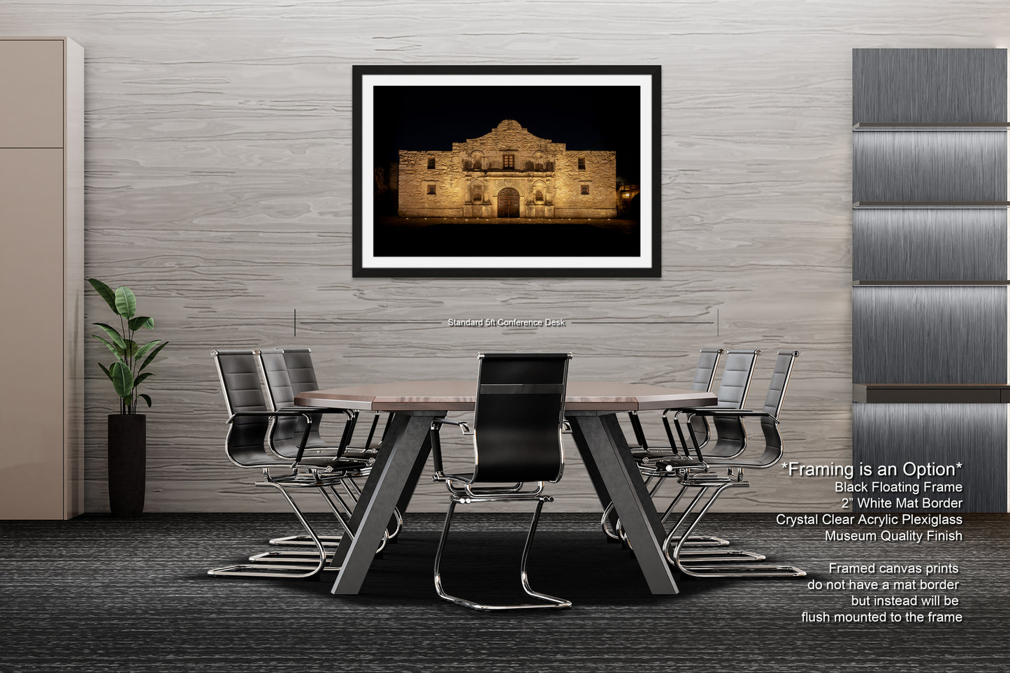 a modern office space with a large framed photograph of the Alamo on the wall, a wooden table surrounded by black chairs, and a plant in a black pot on the floor.