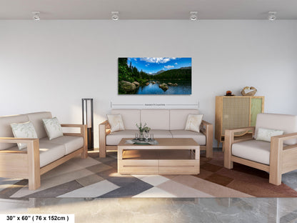 a living room with a large landscape painting hanging on the wall. The painting features a serene lake surrounded by mountains, creating a peaceful and natural atmosphere. The room is furnished with a sofa, two chairs, and a coffee table, providing a comfortable and inviting space for relaxation and socializing.
