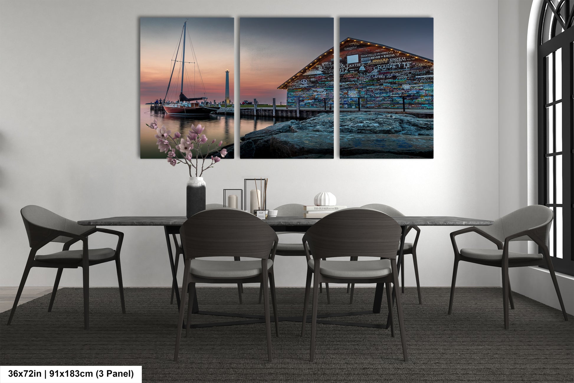 A bedroom with a large bed, nightstands, and a painting of a boat on a dock. The painting is a triptych, with the top and bottom panels depicting a sunset over a body of water. The painting is framed and hangs on the wall above the bed.