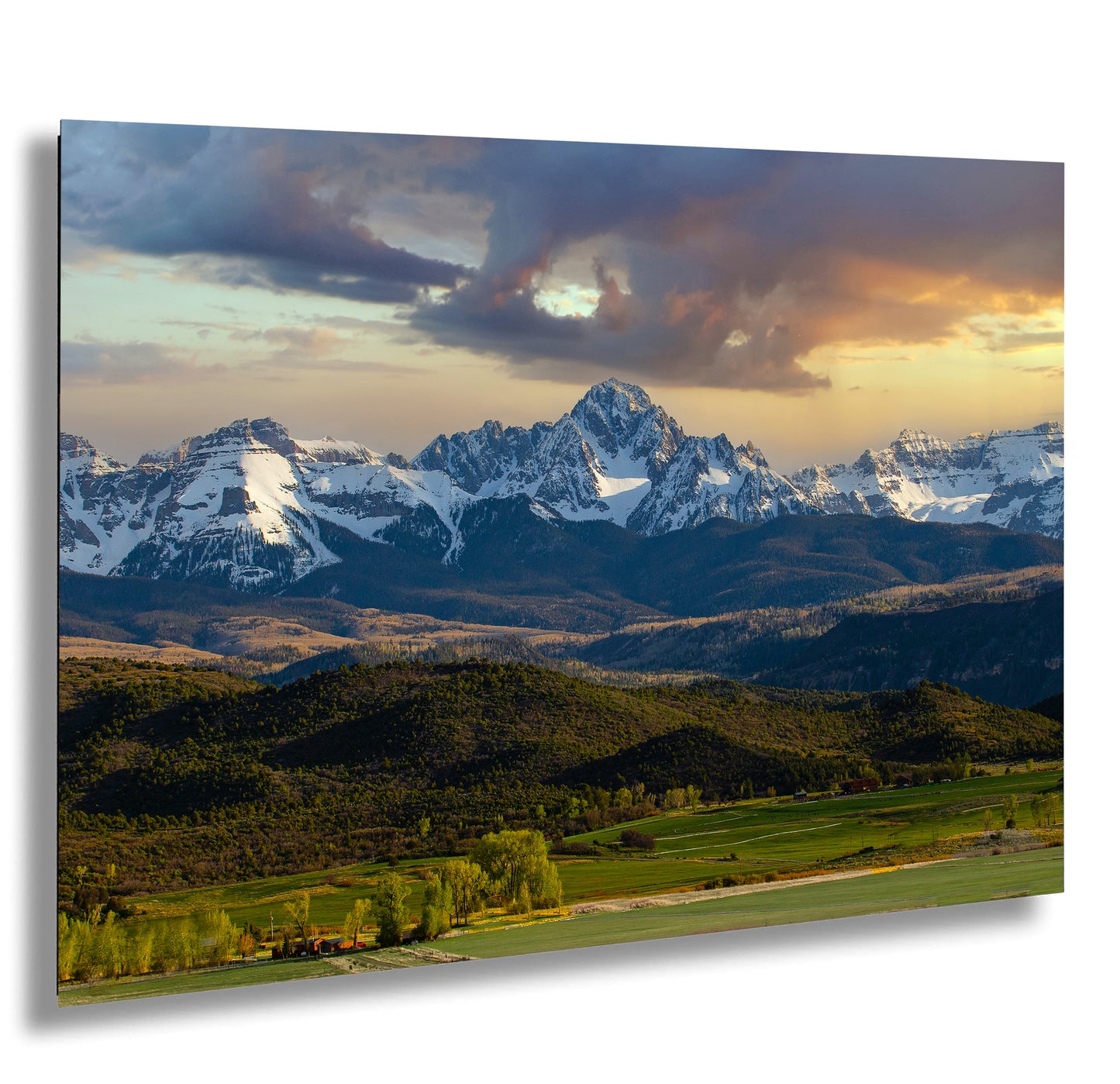 a breathtaking mountain range with snow-capped peaks against a vibrant sky, surrounded by lush green forests and rolling hills.