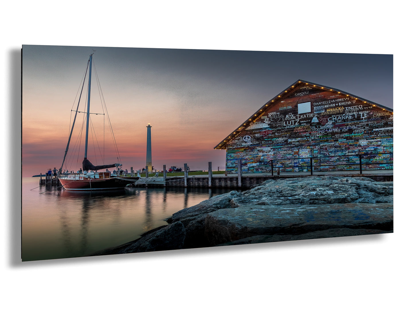 a modern office space with a large black office chair, a wooden conference table, and a framed artwork depicting a serene harbor scene at sunset.