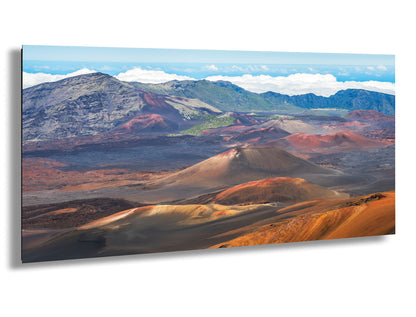 a breathtaking view of a mountainous landscape with a mix of red, orange, and brown hues, suggesting a desert or desert-like terrain. The mountains in the background are covered in lush green vegetation, creating a striking contrast with the barren and rocky foreground. The sky above is a clear blue, dotted with fluffy white clouds, adding to the overall beauty of the scene.
