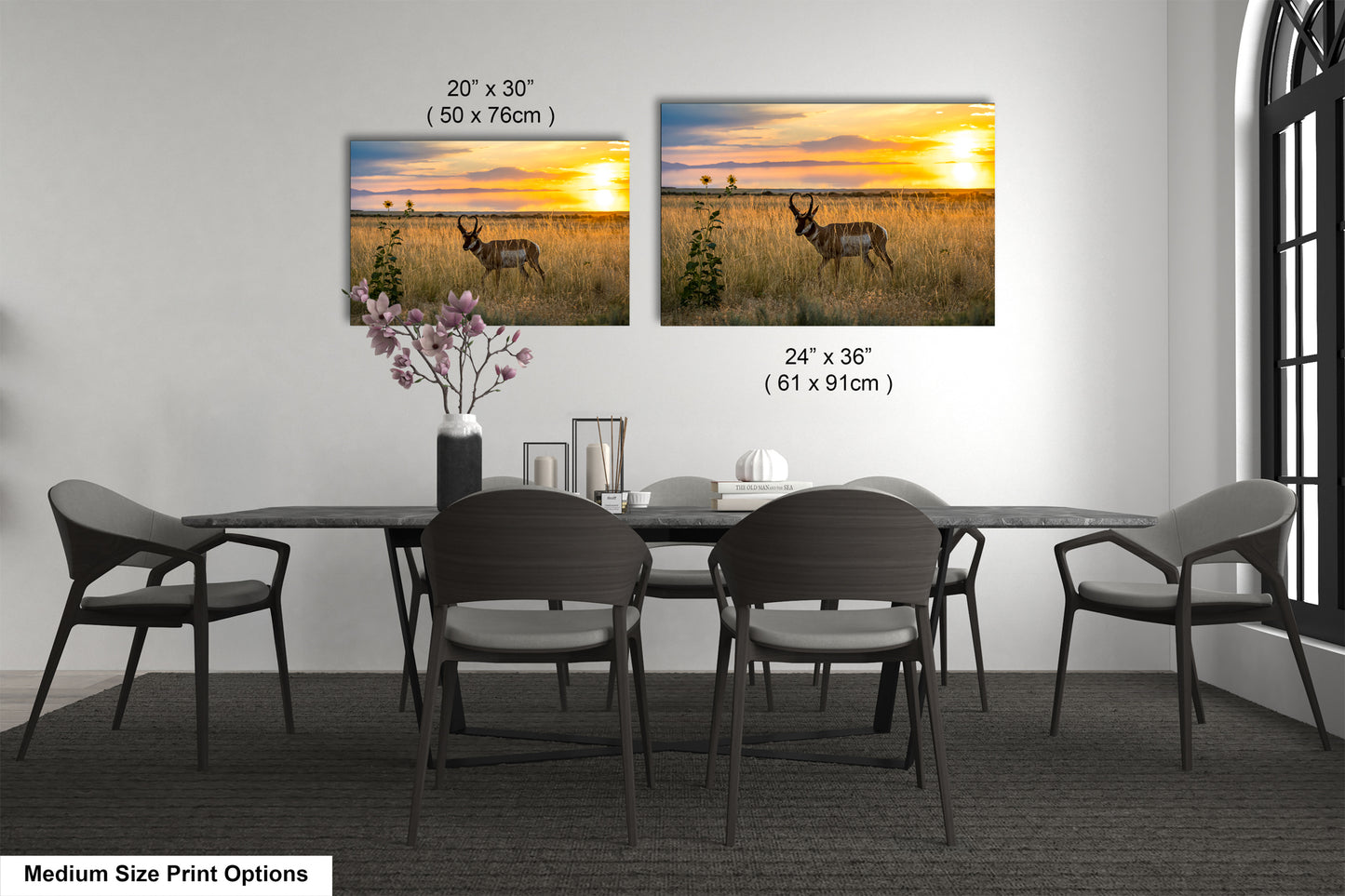 a dining room with a large dining table surrounded by chairs. There are two framed prints of a sunset landscape displayed on the wall above the table. The prints are of different sizes, with one being 24 x 36 inches and the other being 20 x 30 inches.
