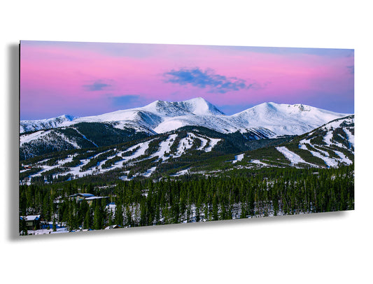 a snowy mountain range with a pink sky in the background