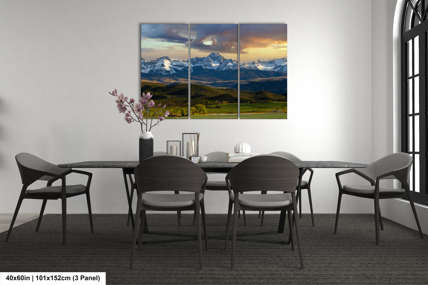 a modern dining room with a large, three-panel landscape painting of a mountain range hanging on the wall above a black dining table surrounded by six chairs.
