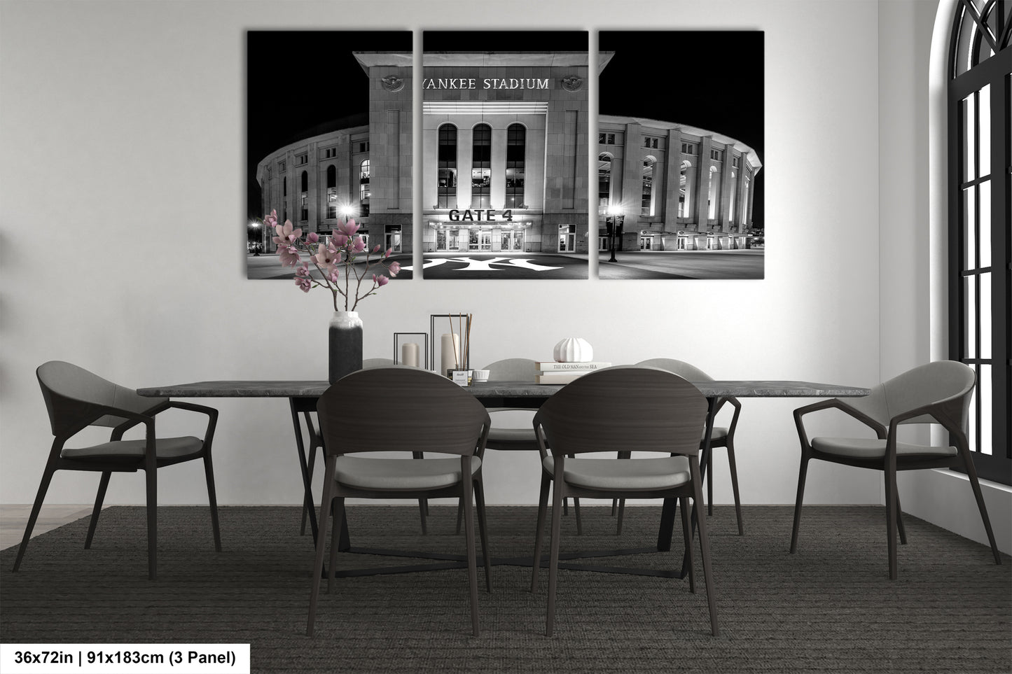 A black and white photograph of Yankee Stadium at night, with a vase of flowers on the table in front of it.