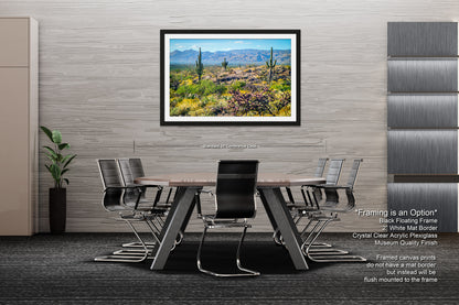 a modern office space with a large framed landscape painting hanging on the wall above a wooden table surrounded by black chairs.