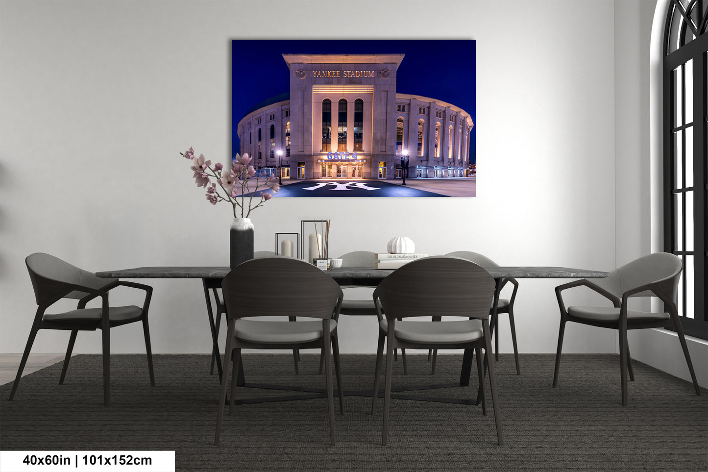 a large, illuminated stadium at night, with a dining table and chairs in front of it.