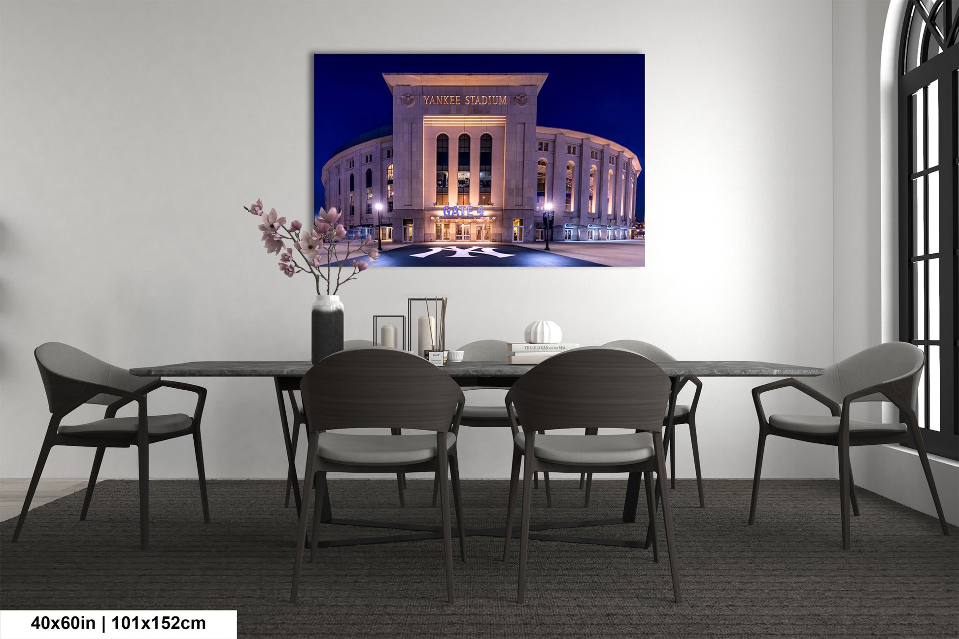 a large, illuminated stadium at night, with a dining table and chairs in front of it.