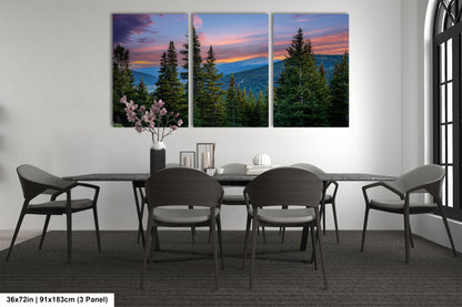 a modern dining room with a large, three-panel landscape painting depicting a mountain range at sunset. The painting is hung on the wall above a black dining table surrounded by matching chairs. The room has a minimalist and contemporary design, with a vase of flowers and a few decorative items on the table.