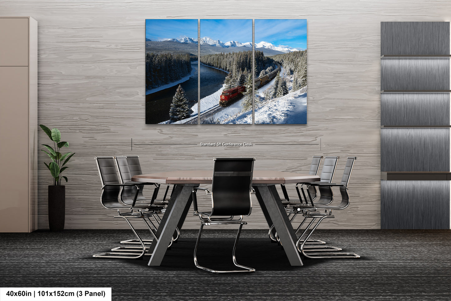 The image is a modern office space with a large, three-panel landscape painting depicting a snowy mountain scene with a train passing through. The painting is mounted on the wall above a wooden table surrounded by chairs.