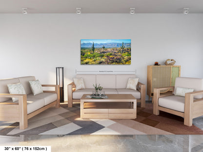 a living room with a large landscape painting hanging on the wall. The painting features a desert scene with mountains in the background. The room is furnished with a sofa, two chairs, and a coffee table. The furniture appears to be made of wood and has a neutral color palette. The painting is approximately 30 inches wide and 76 millimeters high, with a total area of 150 square centimeters.