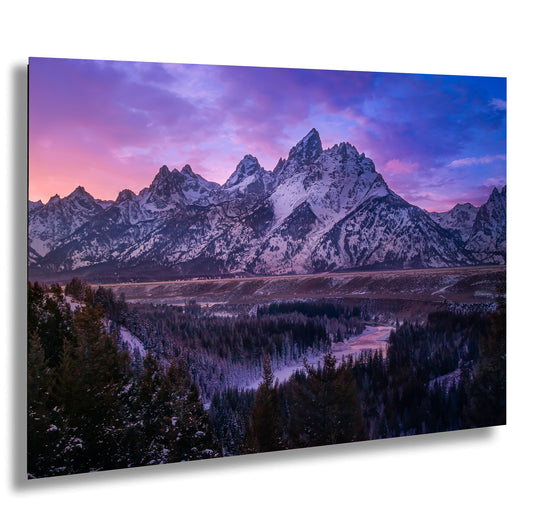 a mountain range covered in snow at sunset