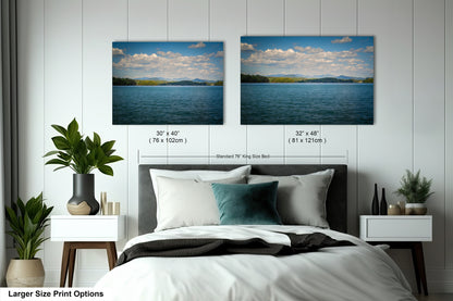 a bedroom with a large bed and two framed landscape photographs hanging on the wall above it.