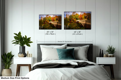 a bedroom with a bed, nightstands, and potted plants. There are two framed landscape photographs hanging on the wall above the bed, depicting a scenic outdoor view. The photographs are of different sizes, with one being larger than the other. The bed is positioned in the center of the room, and the nightstands are on either side of it. The room has a minimalist and modern design, with white walls and a gray floor.
