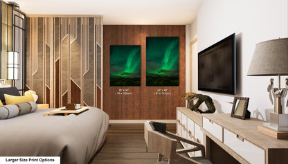 a modern bedroom with a large bed, a wooden dresser, and a television mounted on the wall. There are two framed prints of the northern lights displayed on the wall, and a lamp is also present in the room.