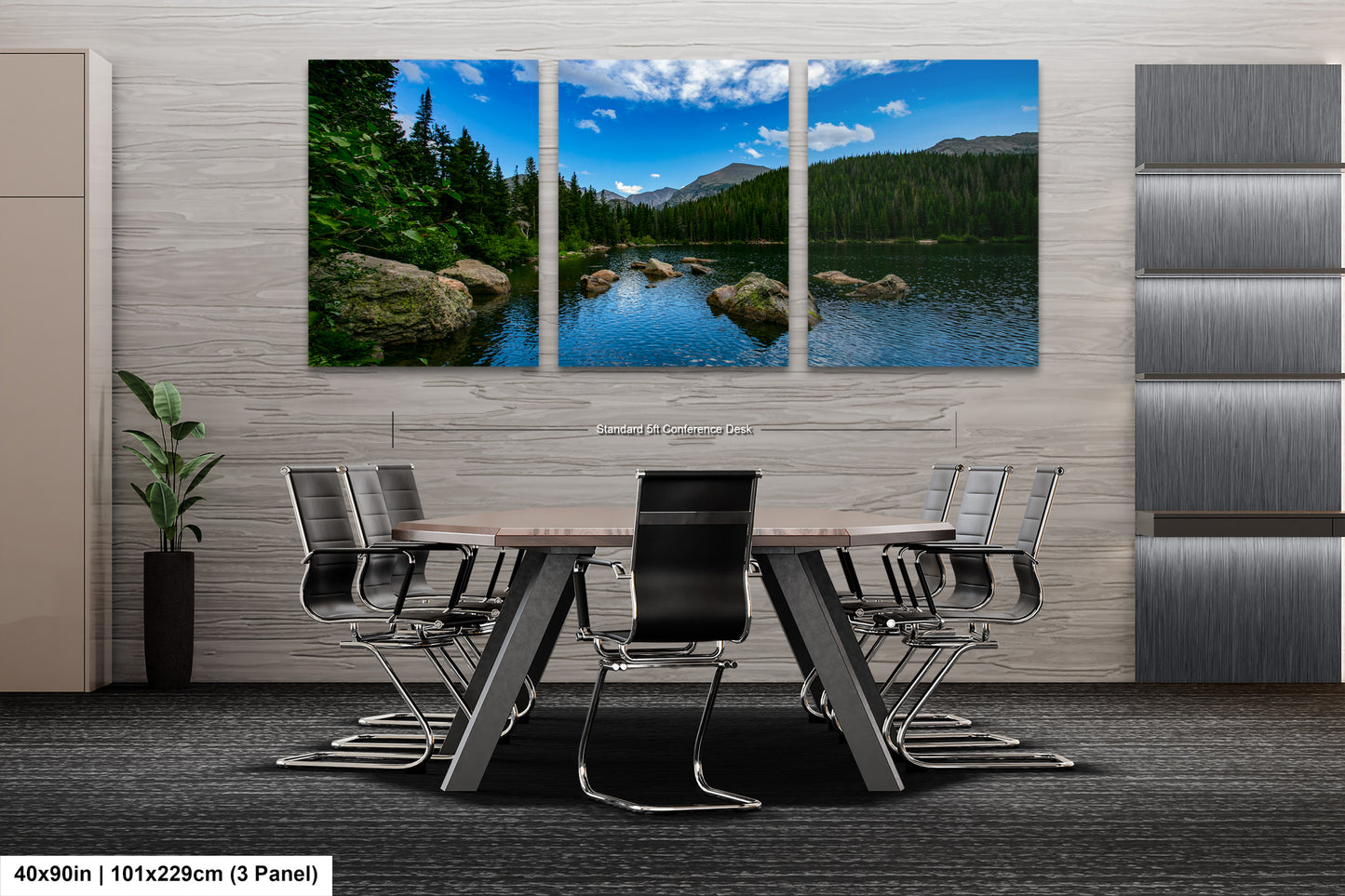 A modern office space with a large, three-panel landscape painting depicting a serene lake surrounded by mountains and trees. The painting is mounted on the wall above a wooden table with chairs.