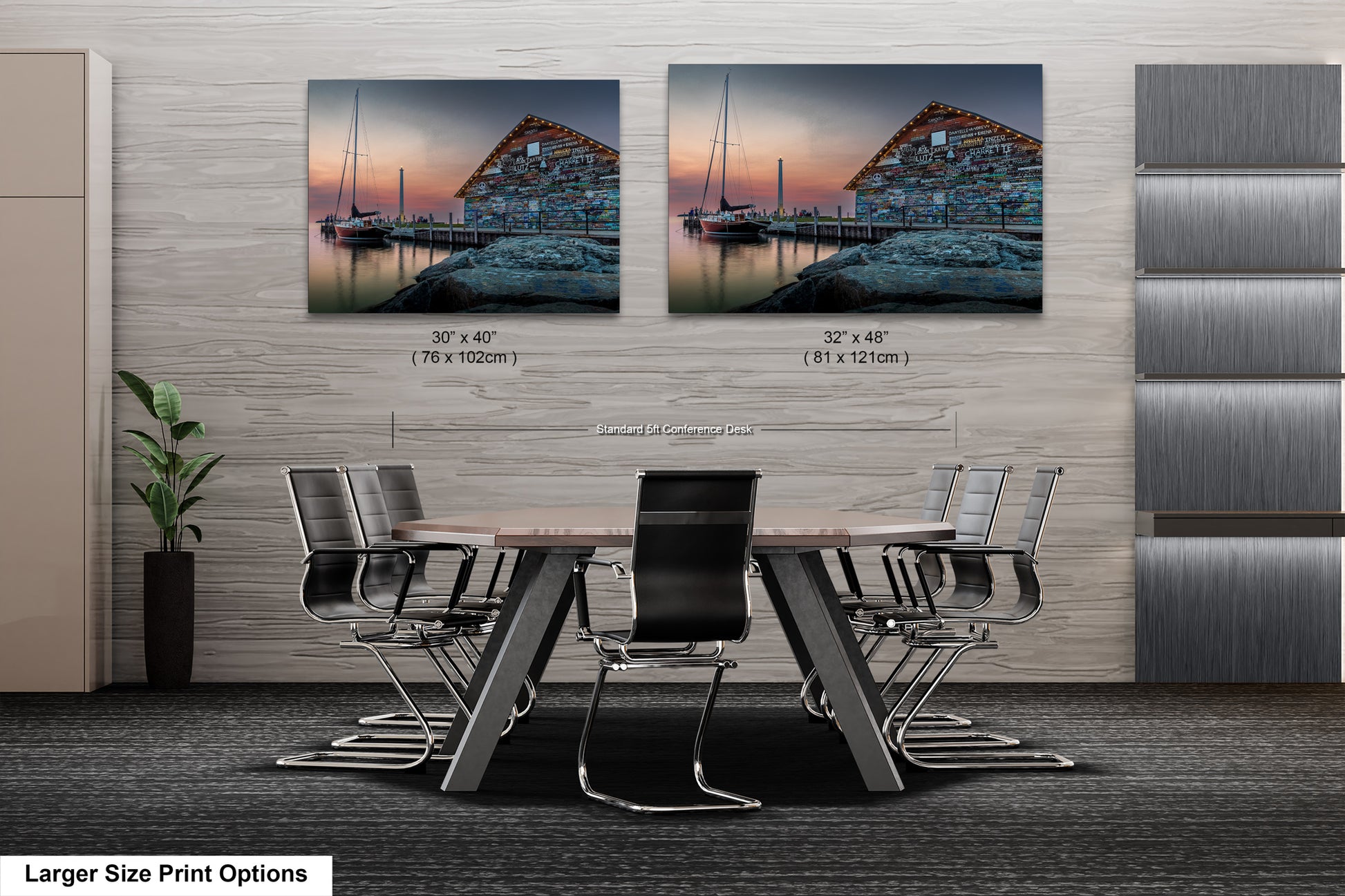 a modern office space with a large wooden table surrounded by black chairs. Two framed prints of a serene harbor scene are displayed on the wall above the table, creating a calming atmosphere.