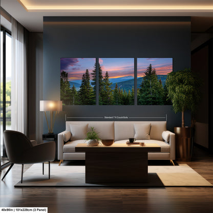 The image is a modern living room with a large, three-panel landscape painting depicting a mountain range at sunset. The painting is hung on the wall above a white sofa and a coffee table. The room also includes a chair, a lamp, and a potted plant, creating a cozy and inviting atmosphere.