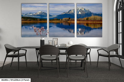 a dining room table with four chairs and three paintings on the wall
