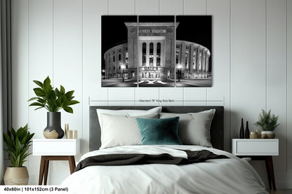 a bedroom with a large black and white photograph of Yankee Stadium hanging on the wall above a bed. The photograph appears to be a collage of multiple images, and the bed is decorated with a gray headboard and white bedding.