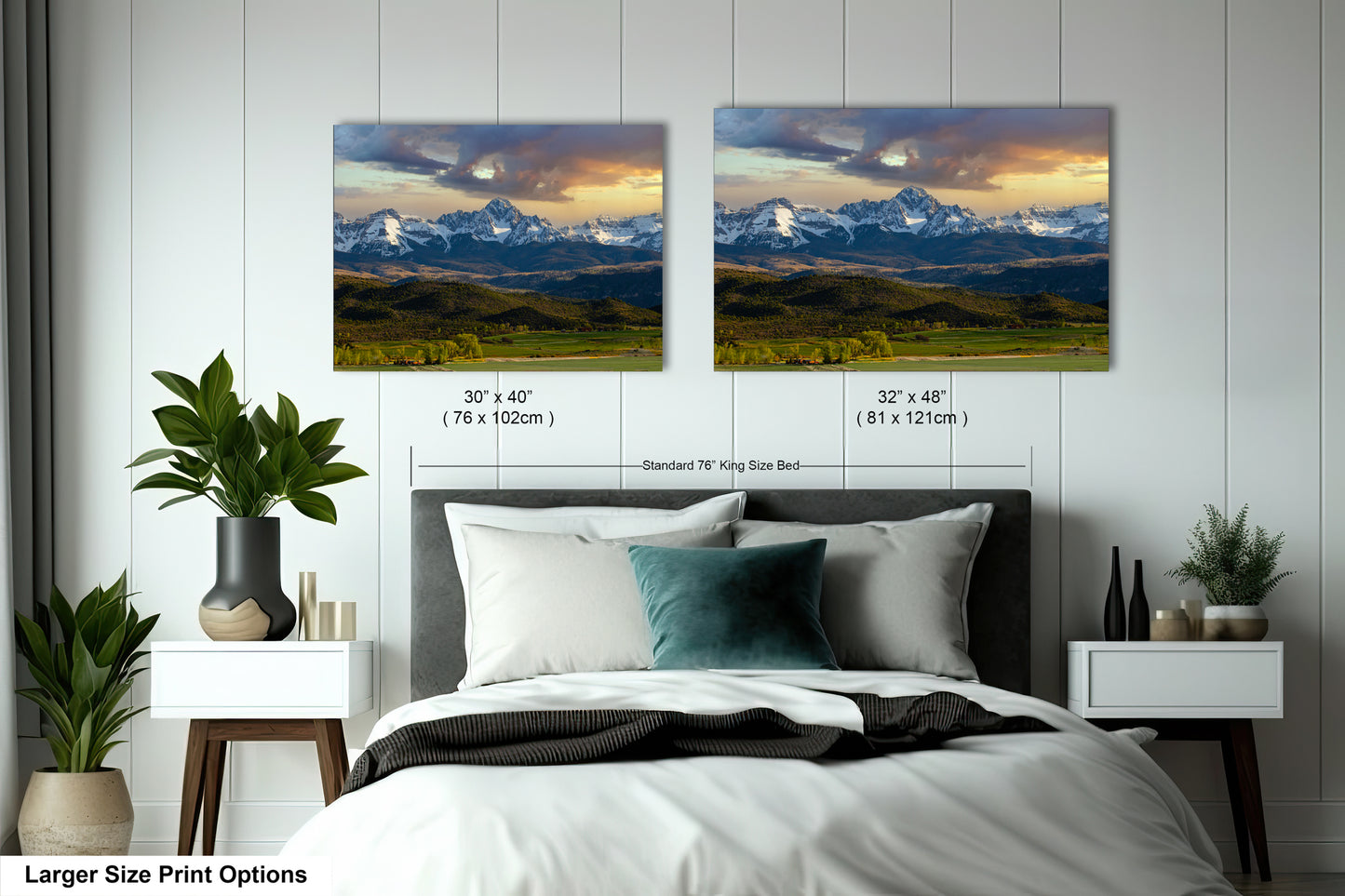 a bedroom with two framed landscape paintings hanging on the wall above a bed. The paintings depict a mountainous, forested landscape with a cloudy sky. The paintings are of similar size and style, suggesting they are intended to be displayed together as a cohesive artwork in the room.