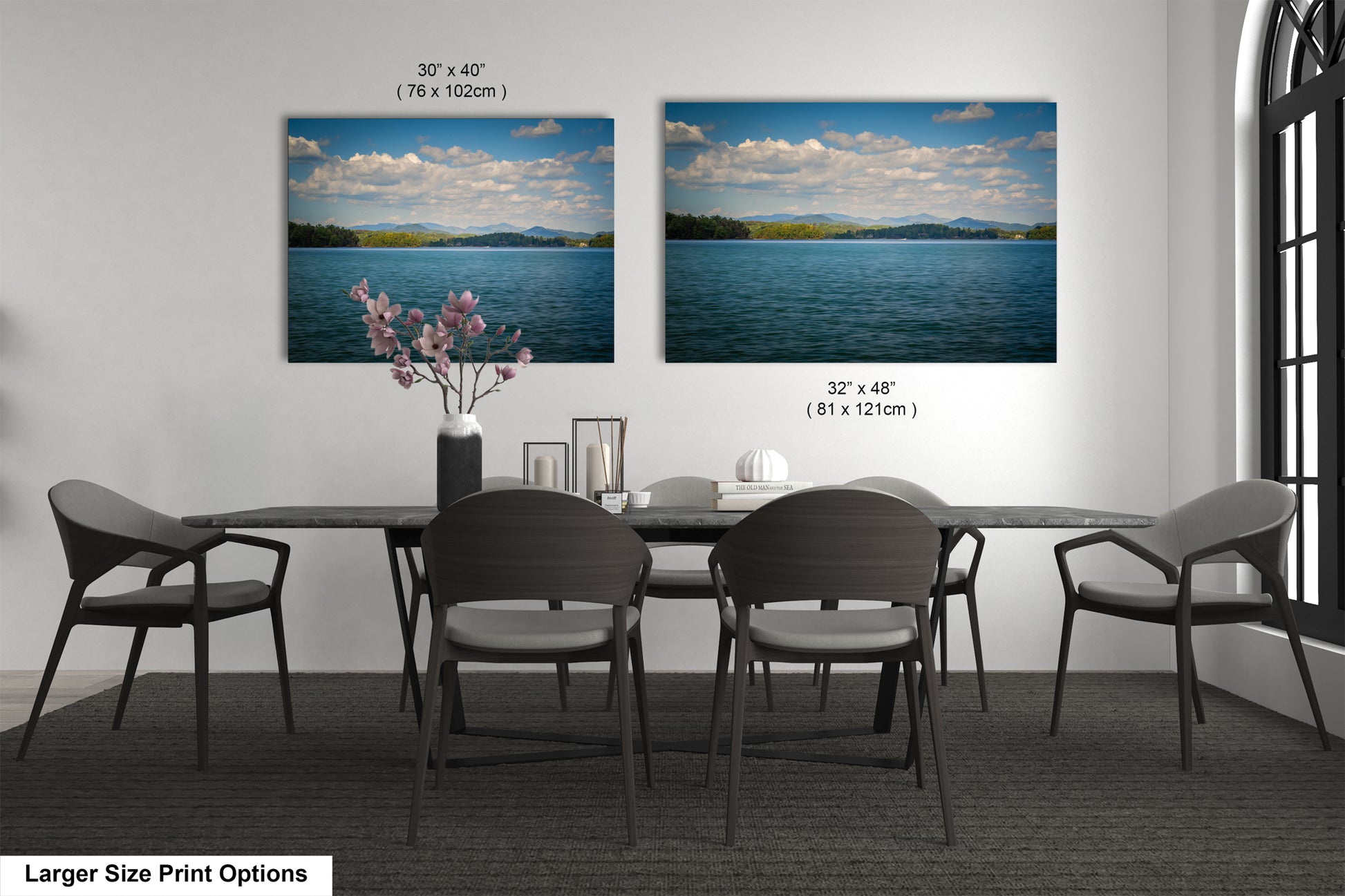 a dining room with a large table and six chairs. There are two framed landscape paintings hanging on the wall above the table, depicting a serene lake scene with mountains in the background. The paintings are of similar size, and the dimensions are provided in the image.