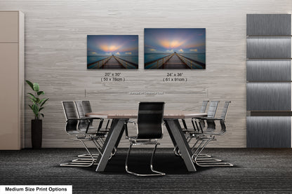 a dining room table with four chairs and two pictures on the wall