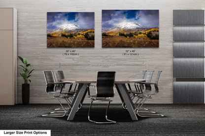 a dining room table with chairs in front of a wall with two pictures of mountains