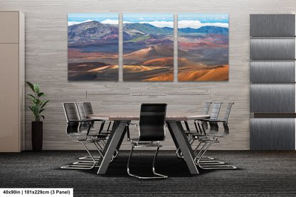 a modern office space with a large, three-panel landscape painting of a desert scene hanging on the wall. The painting is composed of various shades of orange, brown, and blue, creating a striking visual effect. In the foreground, there is a conference table surrounded by several chairs, suggesting a professional setting. The overall design of the space is sleek and contemporary, with a focus on functionality and aesthetics.