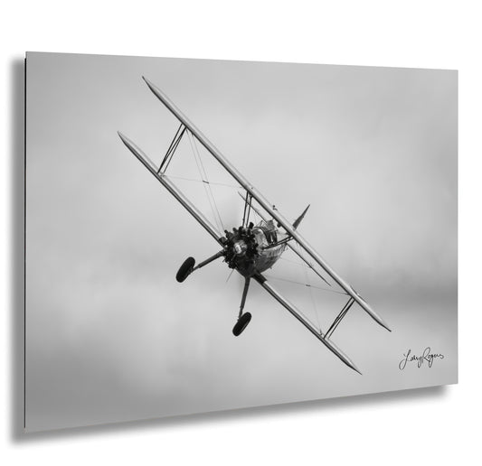 a black and white photo of a biplane flying in the sky