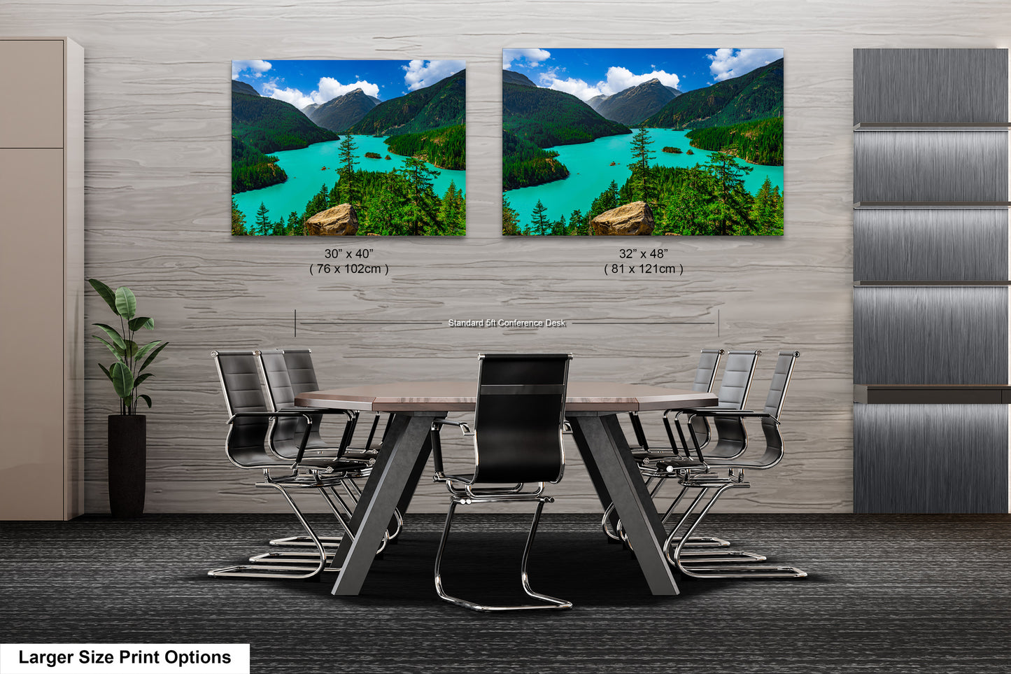 a modern office space with a large wooden table surrounded by black chairs. Two large landscape paintings are displayed on the wall above the table, depicting a scenic mountain view with a turquoise lake.