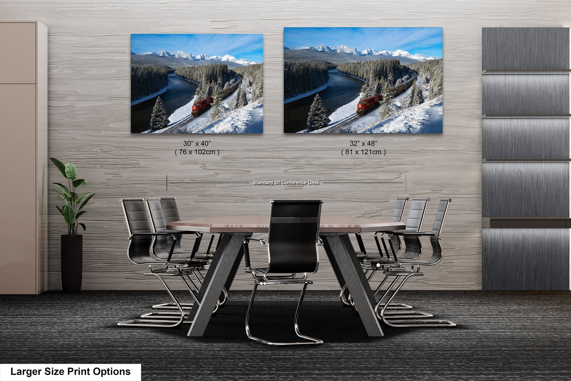 a modern office space with a large wooden table surrounded by black chairs. Two framed landscape photographs are displayed on the wall above the table, depicting snowy mountain scenery and a train on a track.