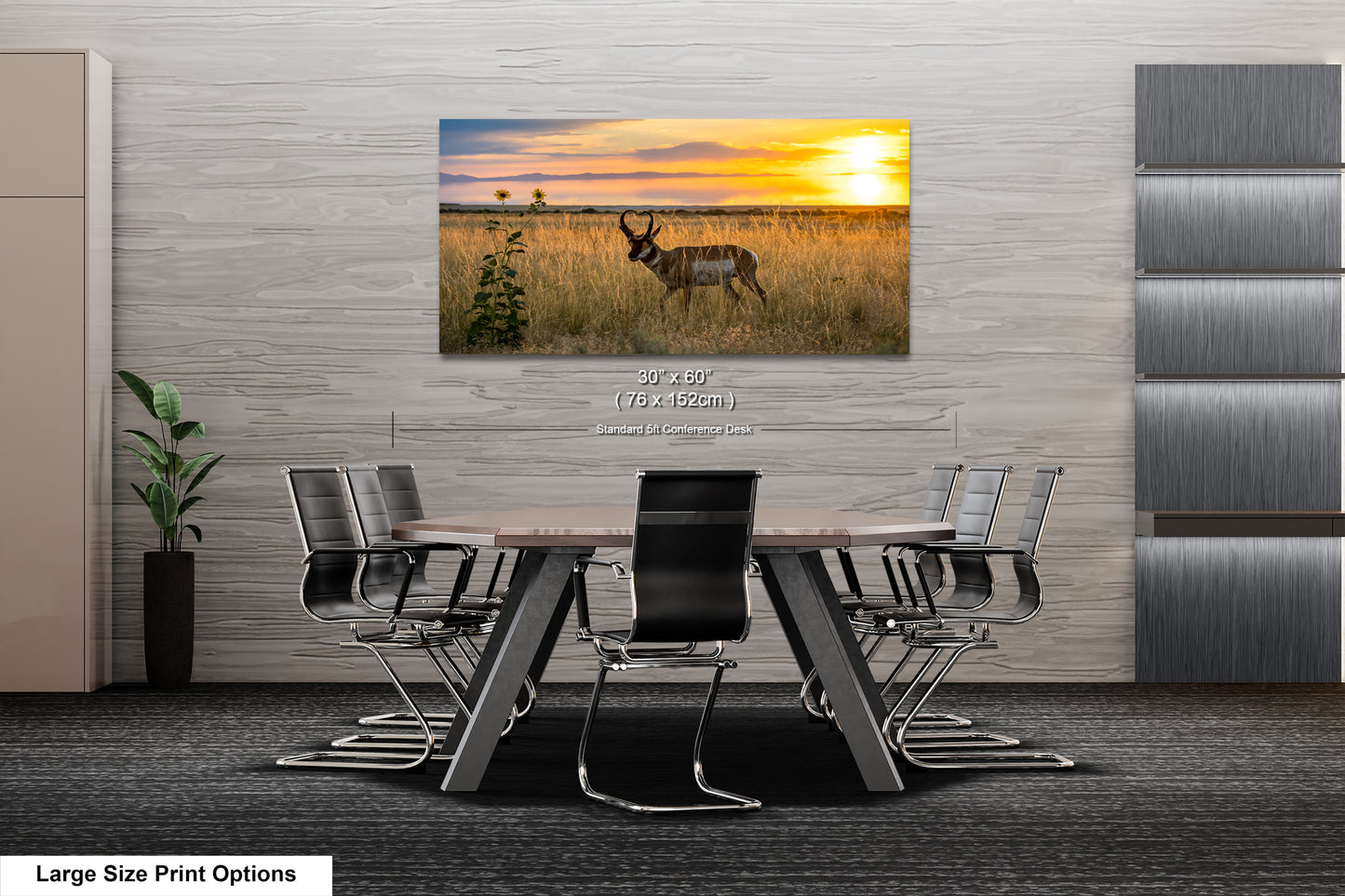 A large-sized print of a serene landscape featuring a gazelle in a field with a sunset in the background is displayed on the wall above a modern office meeting table.