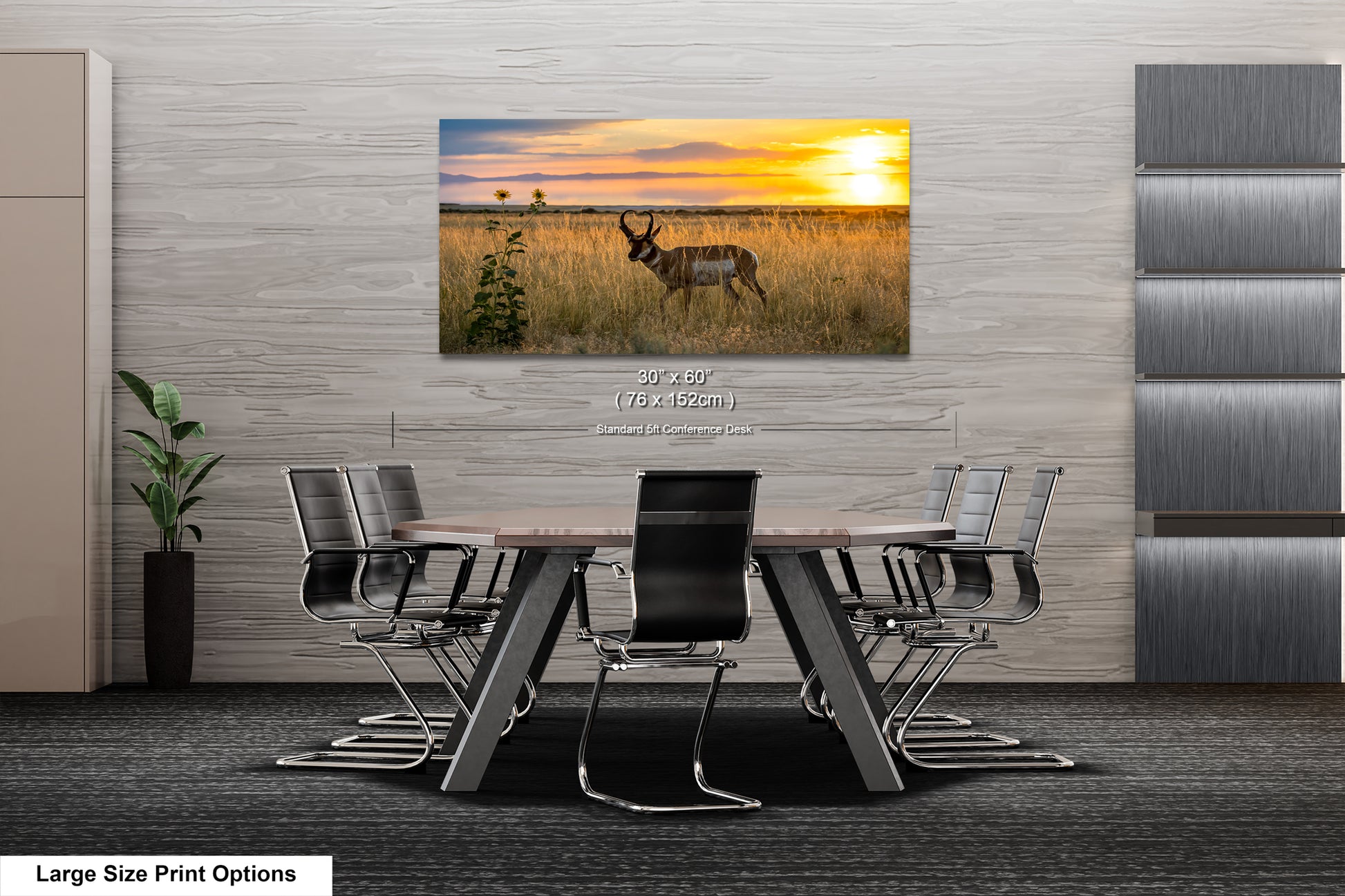 A large-sized print of a serene landscape featuring a gazelle in a field with a sunset in the background is displayed on the wall above a modern office meeting table.