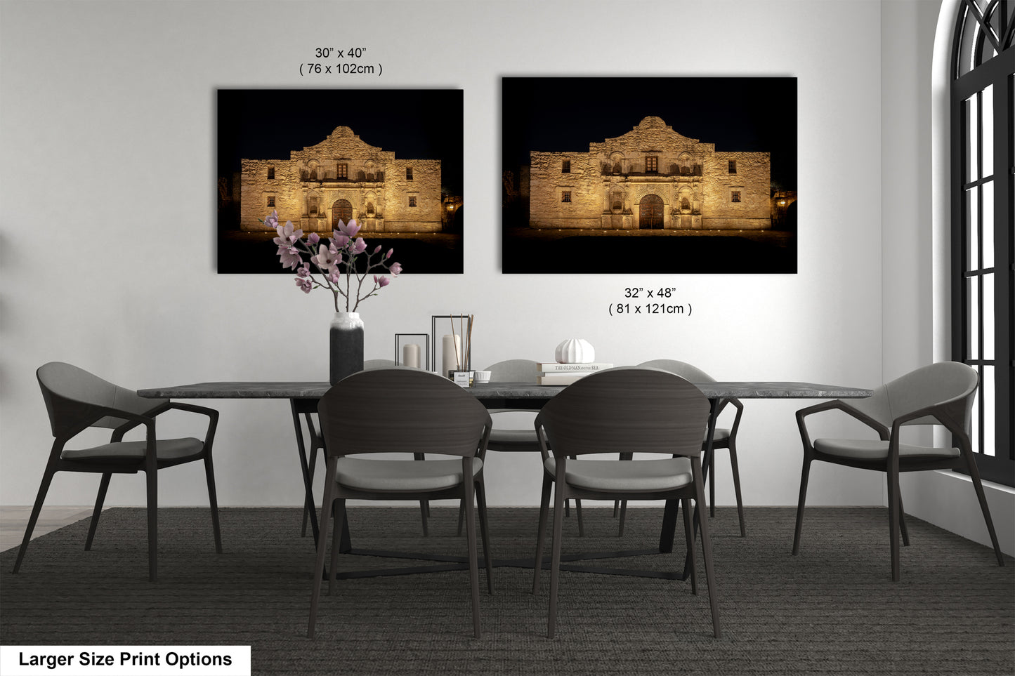 a dining room with a large dining table and six chairs. There are two framed photographs of the Alamo, a historic landmark, hanging on the wall above the table. The photographs are of different sizes, with one being larger than the other.