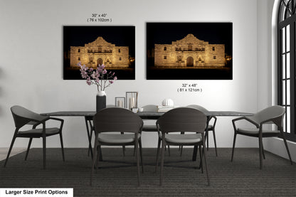 a dining room with a large dining table and six chairs. There are two framed photographs of the Alamo, a historic landmark, hanging on the wall above the table. The photographs are of different sizes, with one being larger than the other.
