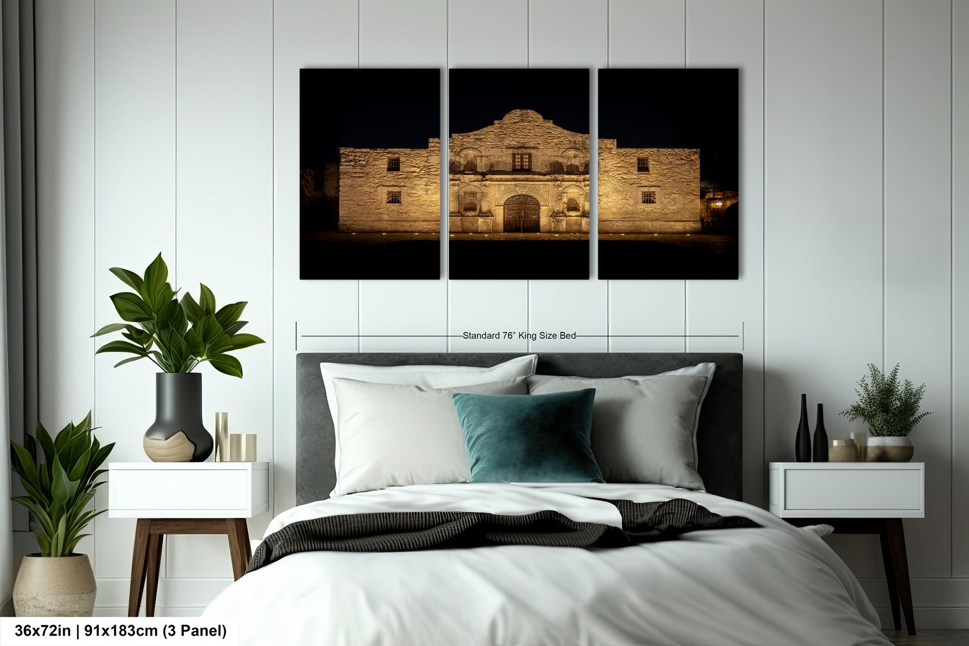 A bedroom with a large bed, nightstands, and a potted plant. Above the bed is a large framed photograph of a building, likely a historic structure, illuminated at night.