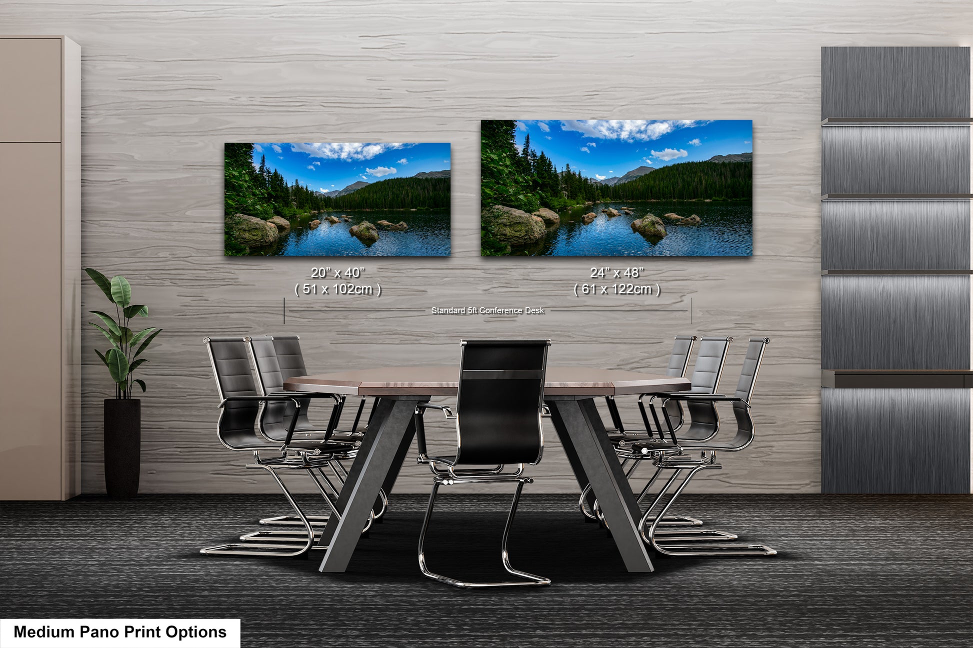 a modern office space with a large wooden table surrounded by black chairs. Two framed landscape photographs are displayed on the wall above the table, depicting a serene natural scene with a lake and mountains in the background.