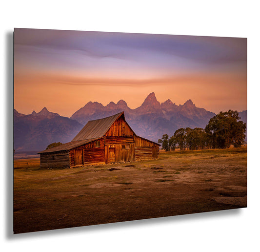 a barn in a field with mountains in the background