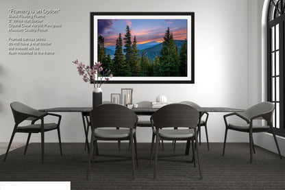 a modern dining room with a large framed landscape painting hanging on the wall above a black dining table surrounded by six chairs. The painting depicts a serene mountain landscape with a colorful sunset sky.