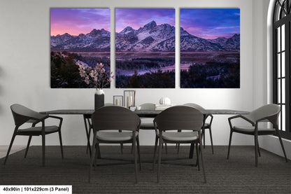 a dining room table with four chairs and three paintings on the wall