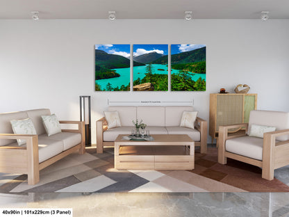 The image is a modern living room with a large, three-panel landscape painting hanging on the wall. The painting depicts a scenic mountain landscape with a turquoise lake and lush green forests. The room is furnished with a sofa, two armchairs, and a coffee table, creating a comfortable and inviting atmosphere.