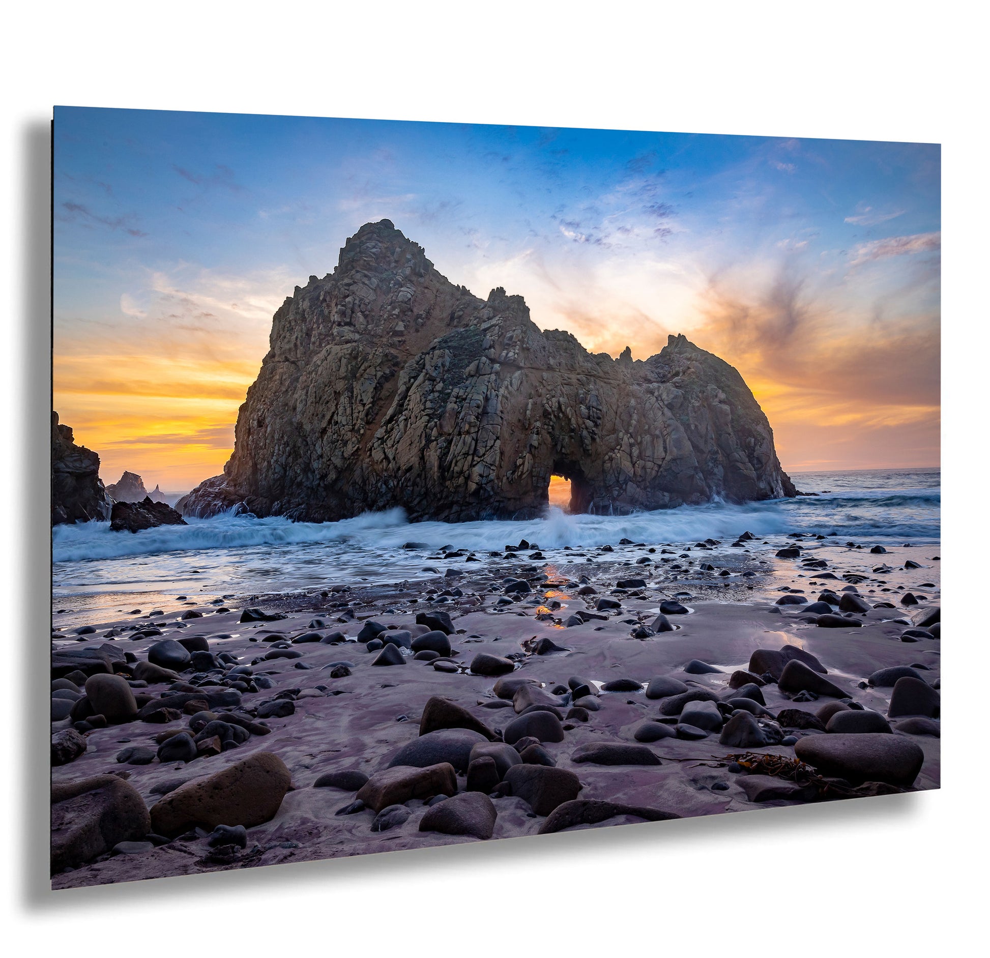 a rock formation on a beach with a sunset in the background