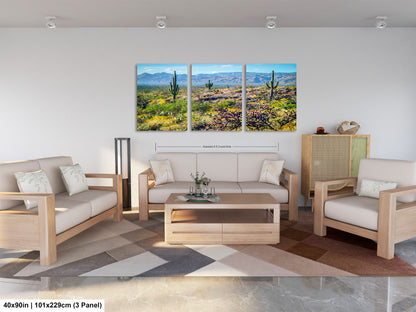 The image is a modern living room with a large, three-panel landscape painting depicting a desert scene with cacti and mountains in the background. The room is furnished with a sofa, two armchairs, and a coffee table, creating a comfortable and inviting atmosphere.