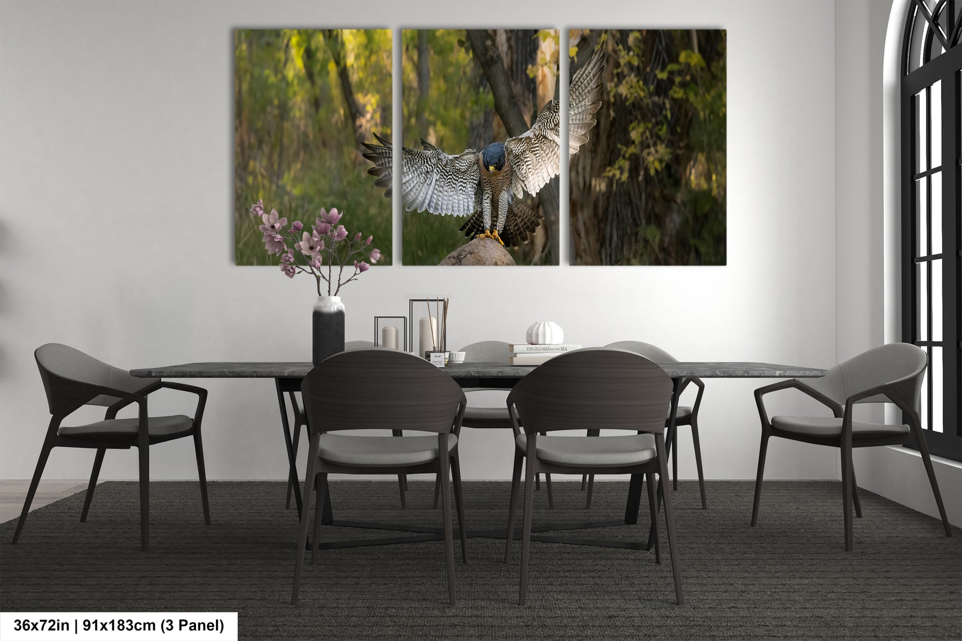 A modern dining room with a large wall-mounted painting depicting a bird in flight. The painting is composed of three panels, with the bird in the center and its wings spread wide. The room is furnished with a black table and chairs, and there is a vase of flowers on the table. The overall design and decor create a sleek and contemporary atmosphere.