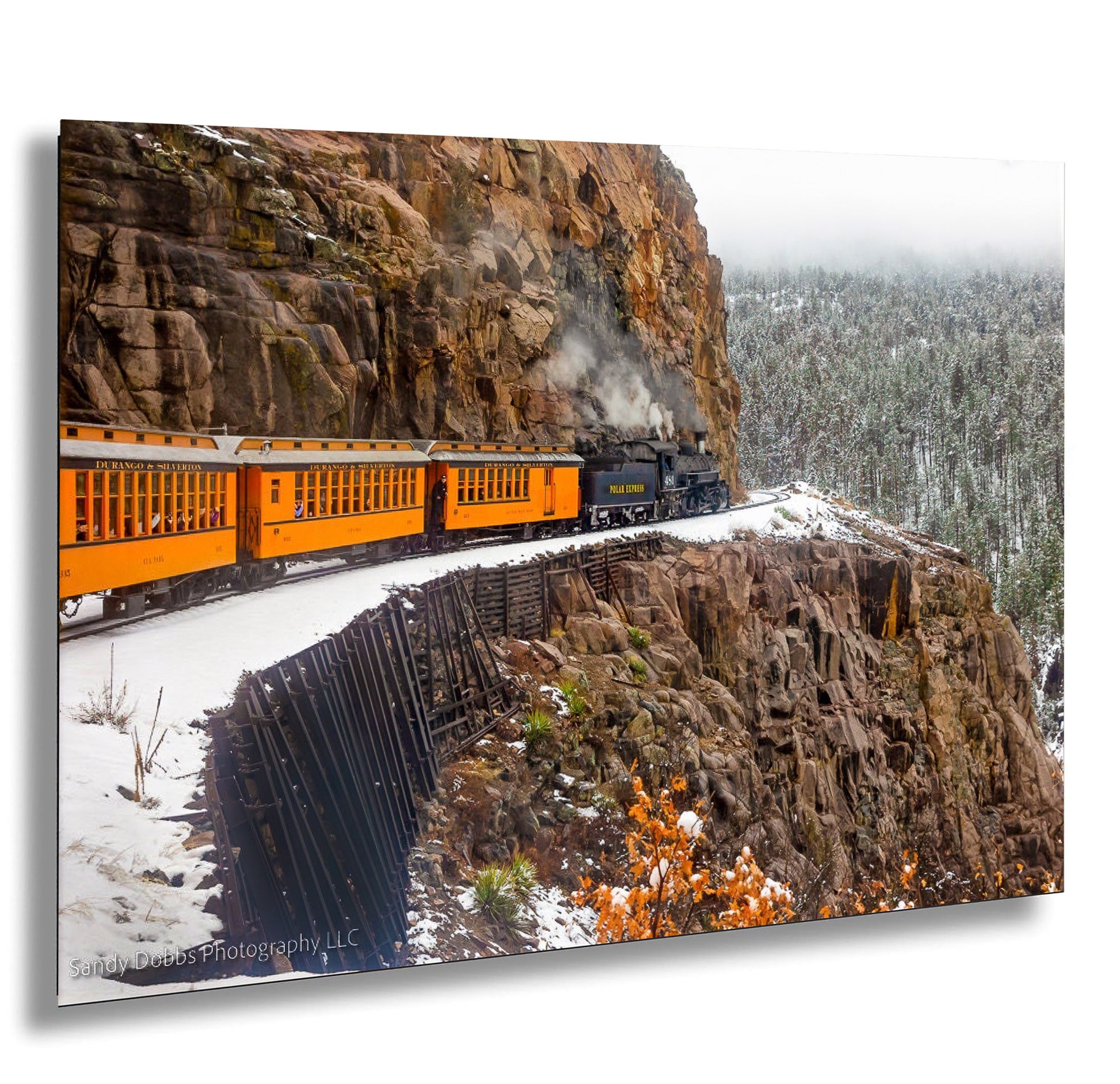 a train traveling down tracks next to a mountain